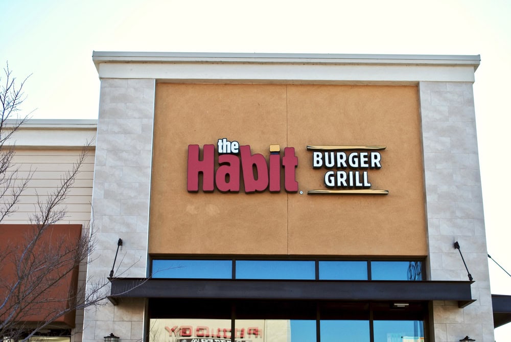 Exterior of The Habit Burger Grill restaurant with a tan facade and red and white signage.