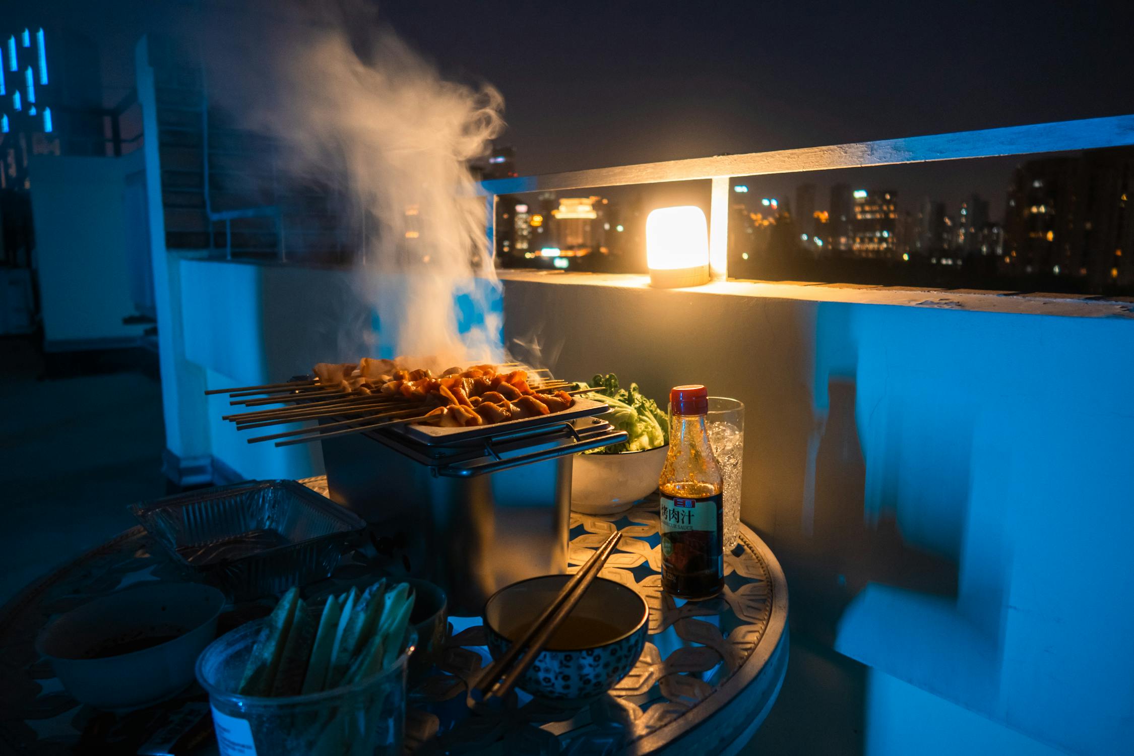 free photo of night rooftop barbecue with skewers