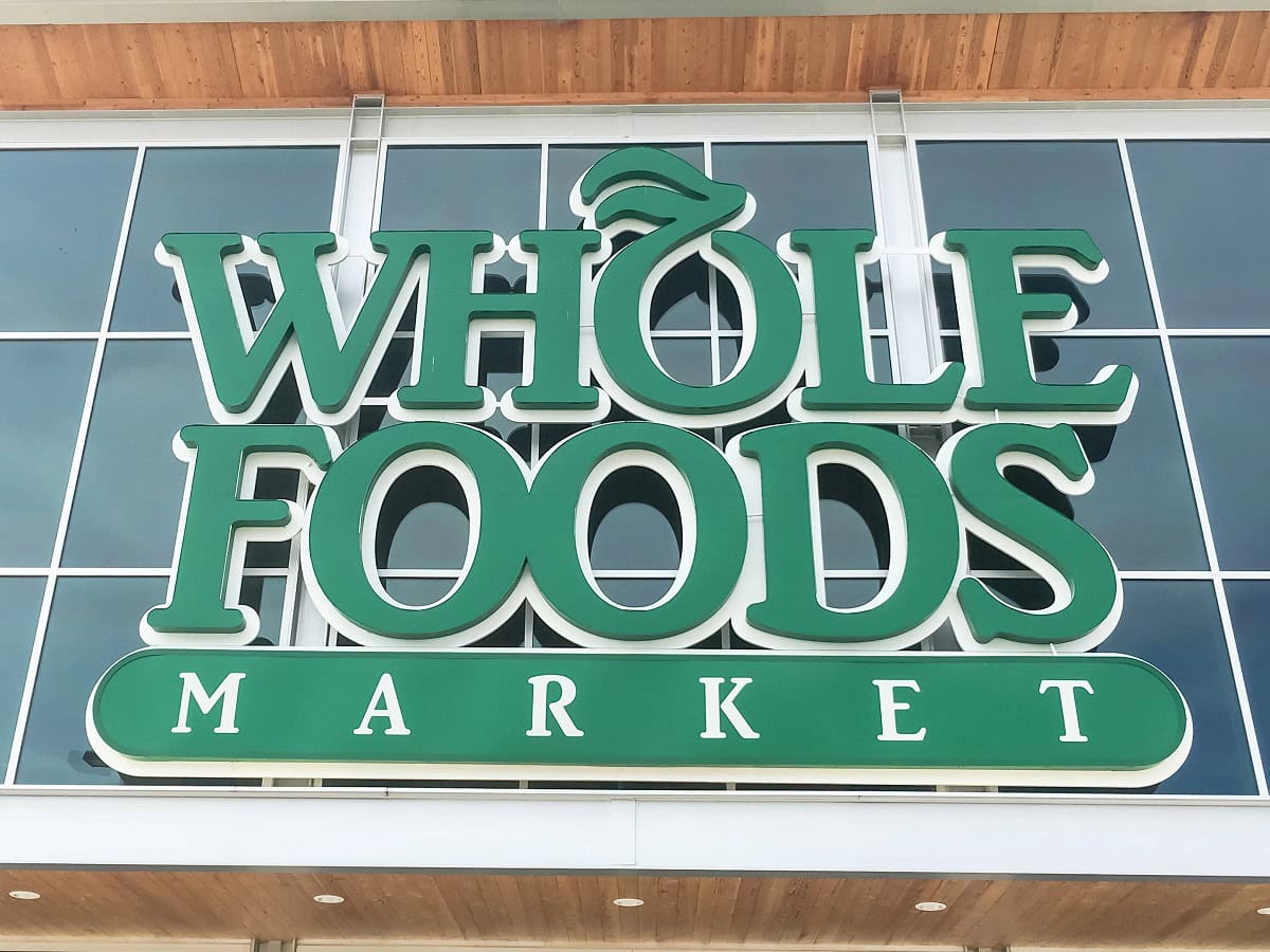 Sign displaying the words "Whole Foods Market" in large green letters with a leaf design on the 'O.'.