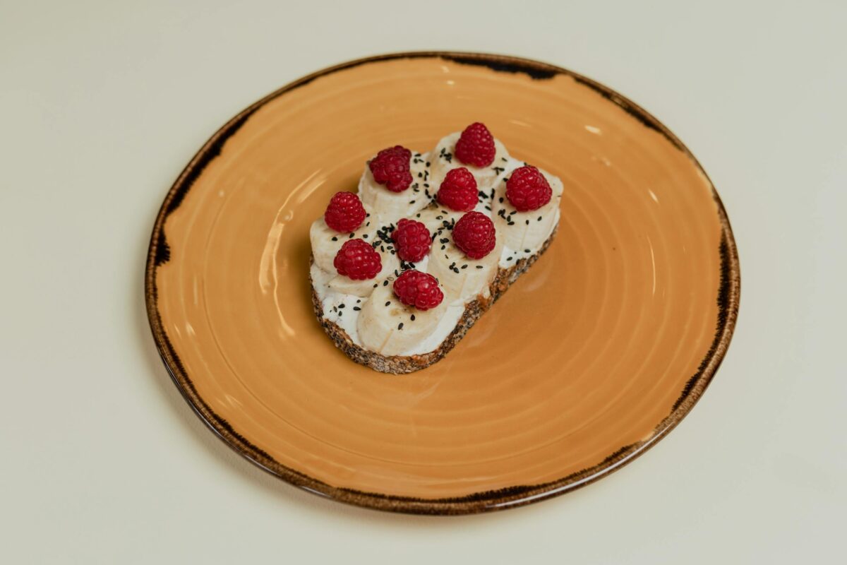 A delectable toast featuring raspberries and banana slices on a stylish ceramic plate.